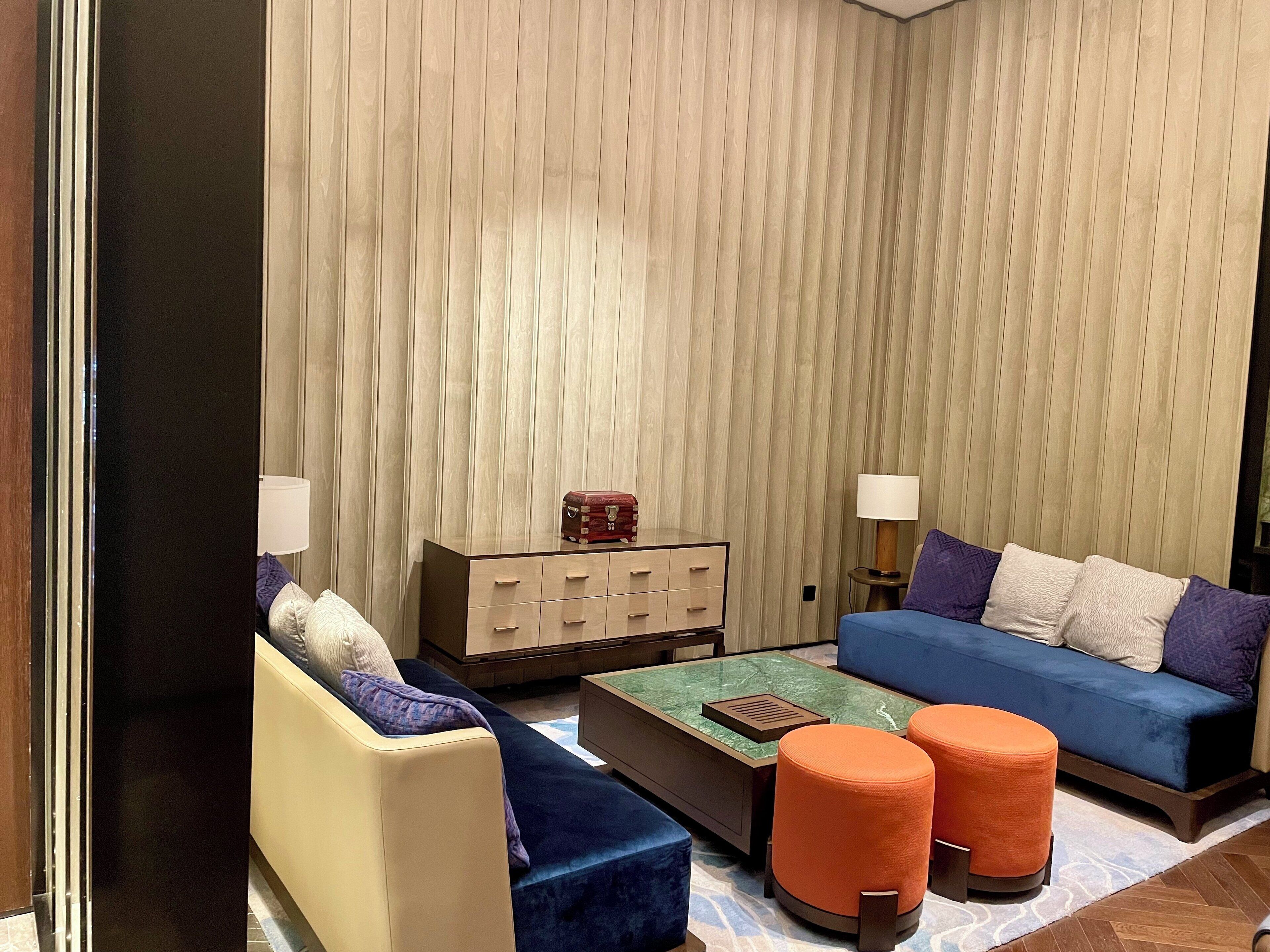 A modern living room with a sofa, ottomans, a coffee table, and a side table with lamps.