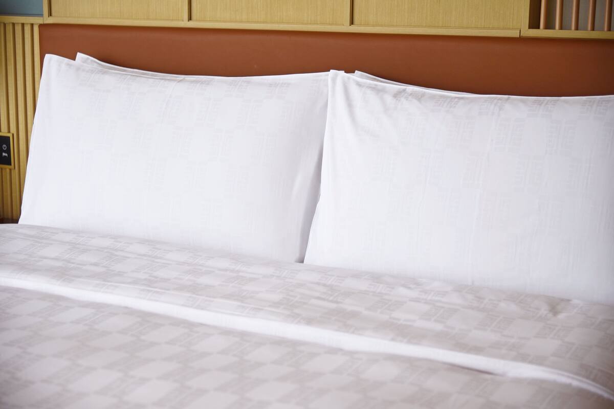 A neatly made bed with a patterned bedspread and two pillows.