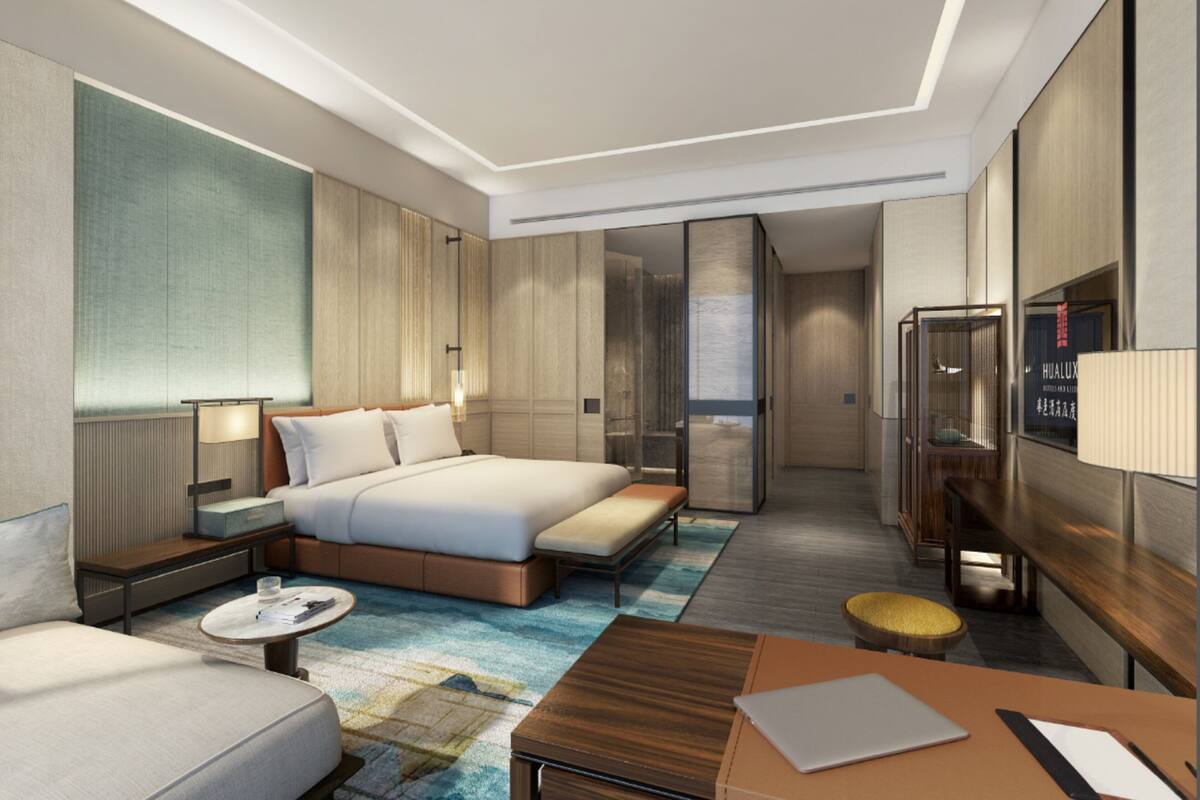 A modern hotel room with a large bed, a desk, a sofa, and a TV.