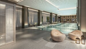 A modern indoor swimming pool with seating areas, stone walls, and a ceiling with a unique pattern. - HUALUXE Yibin by IHG (Yibin)