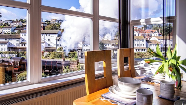 Un comedor con vista a un barrio residencial y un tren de vapor.