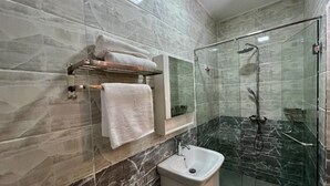 Une salle de bain avec une douche à parois de verre, un lavabo blanc et un porte-serviettes avec des serviettes pliées.