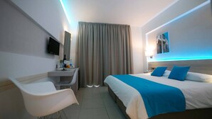 A hotel room with a bed, a desk, a chair, a TV, and a window with curtains. - Les Palmiers Boutique Beach Hotel and Luxury Apartments in Larnaca (Cyprus, Larnaca)