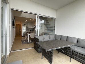 Ein moderner Wohnbereich mit Essbereich, einer Küchenzeile und einer Glastür, die auf einen Balkon führt.