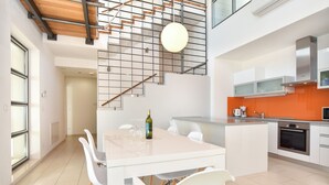 Una cocina moderna con una isla central, sillas blancas y una mesa de comedor.