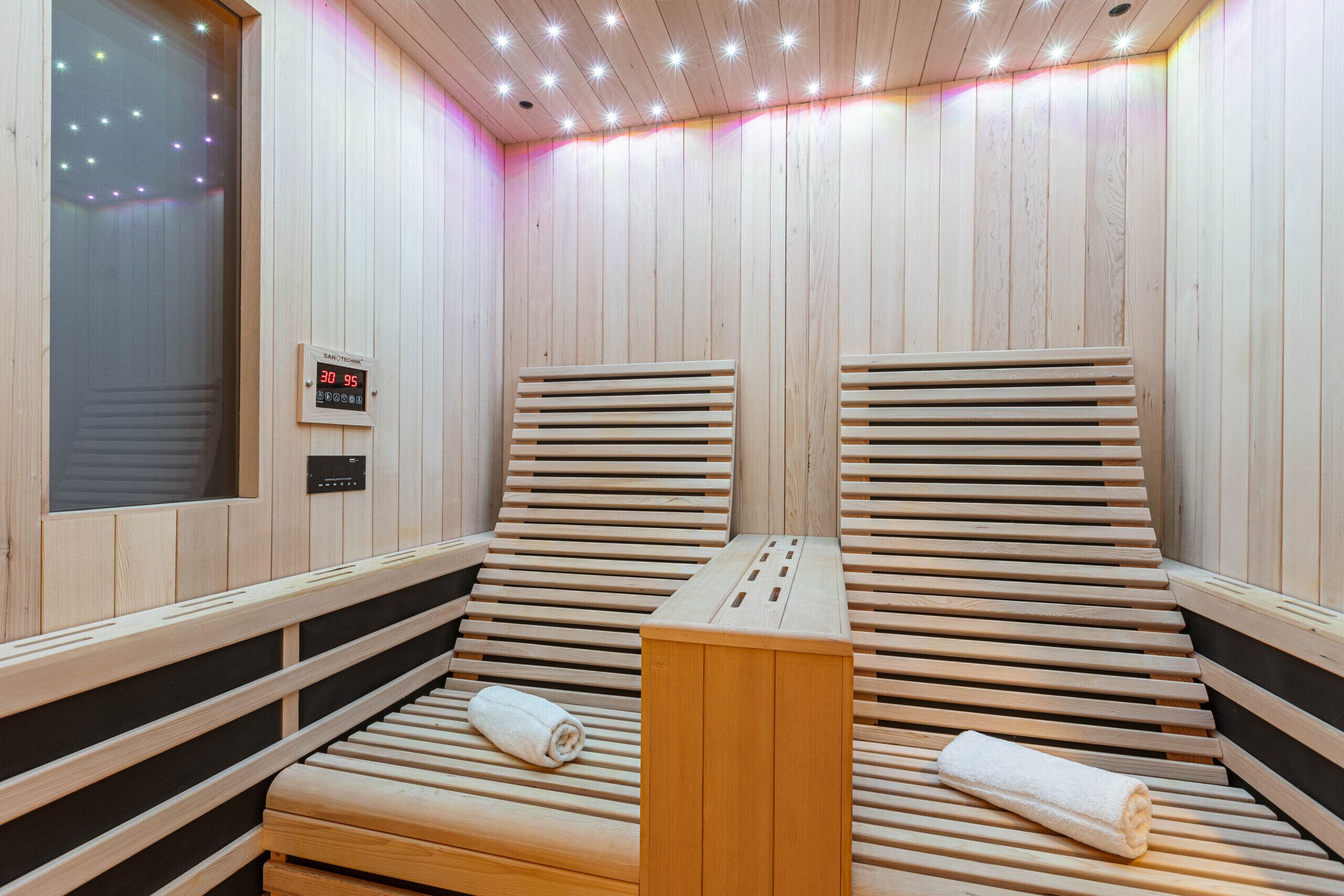 A sauna room with wooden benches and a control panel.