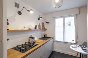 A modern kitchen with a wooden countertop, gas stove, and a window providing natural light.