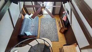 A loft-style room with a high ceiling, exposed beams, a sofa, a rug, and two American flags. - Table Rock Lake Cabin @ Black Oak Resort (Lampe)