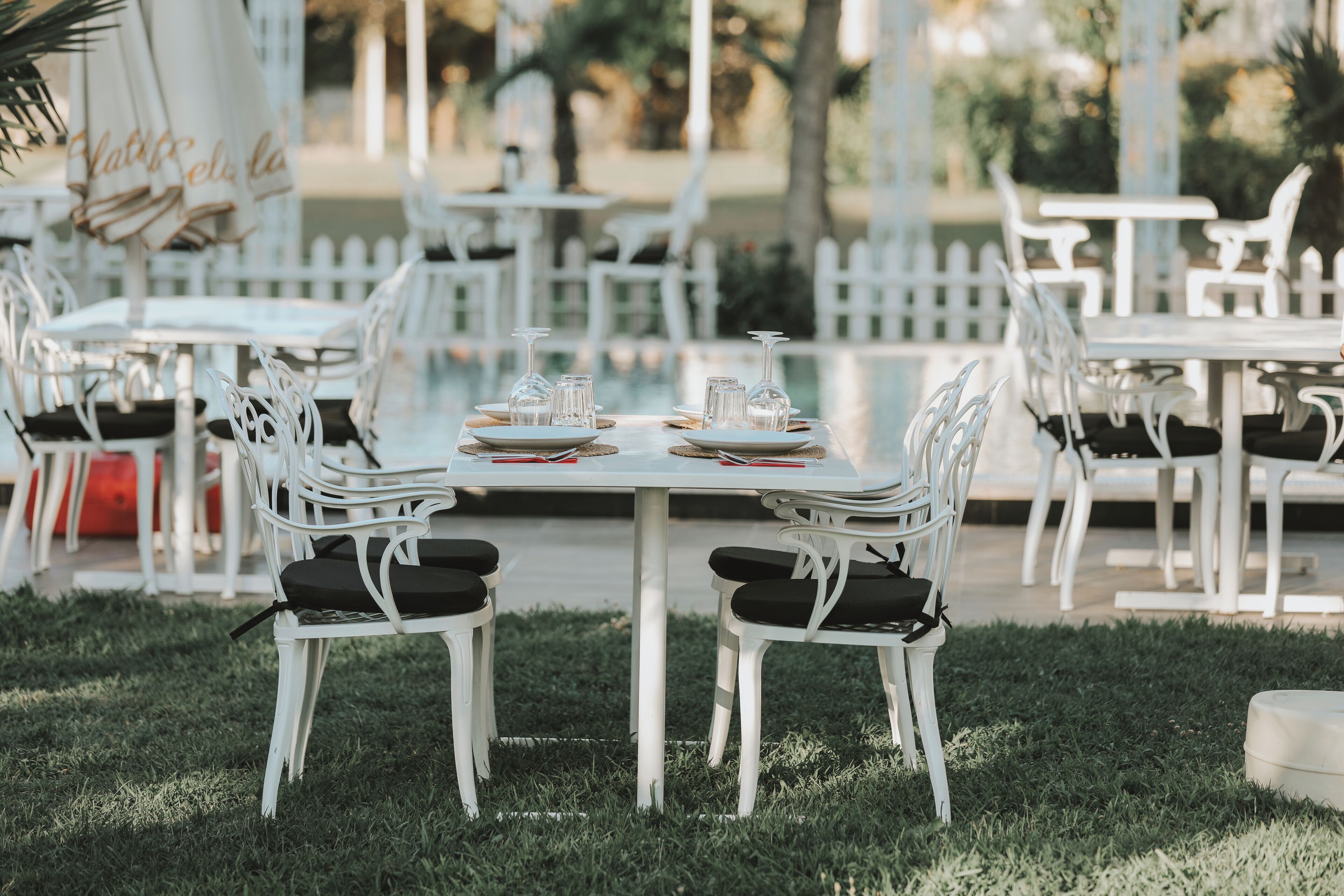 An outdoor dining area with white tables and chairs, arranged in a spacious, open layout.