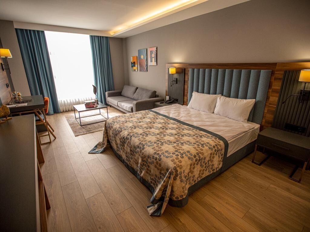 Una habitación de hotel moderna con una cama grande, un sofá, un escritorio y una mesa de comedor.