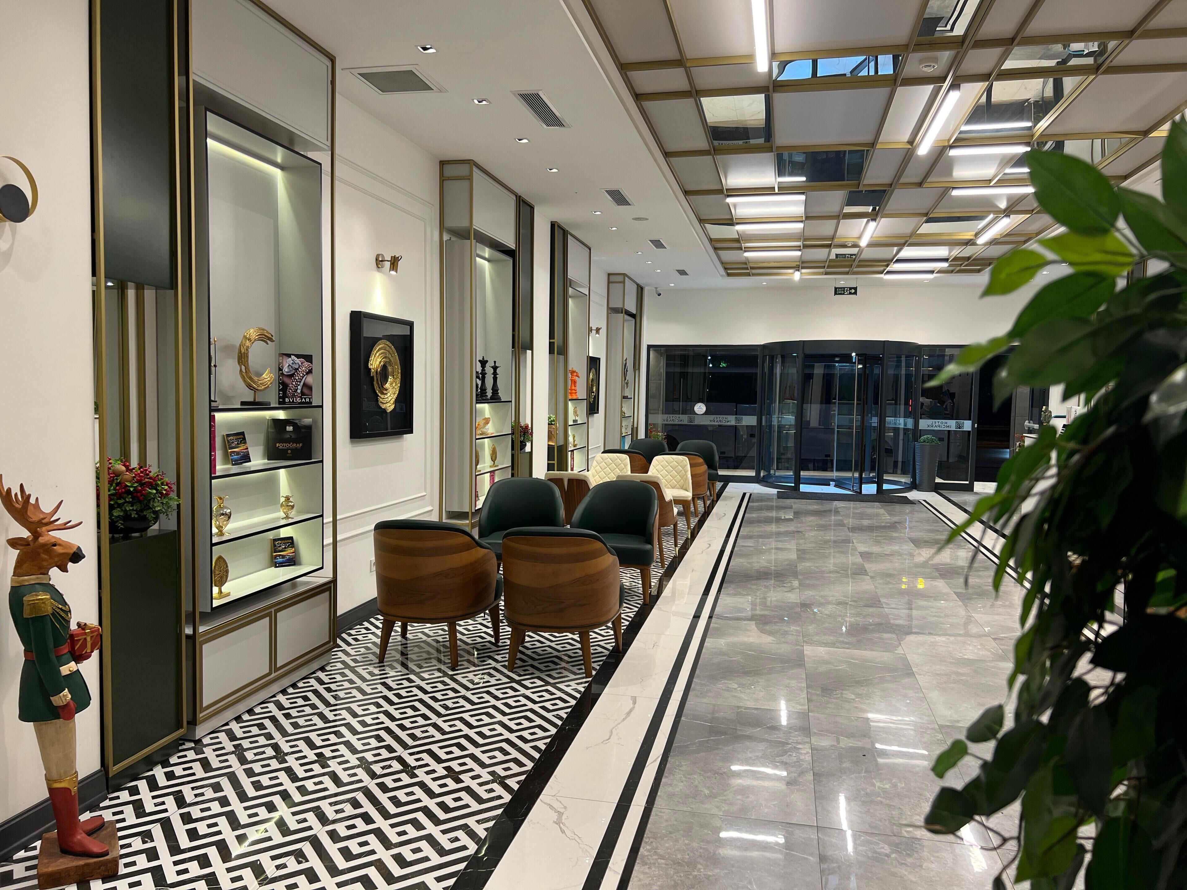 Un hall d’entrée moderne avec un sol à motifs, un espace salon et des vitrines exposant divers objets.
