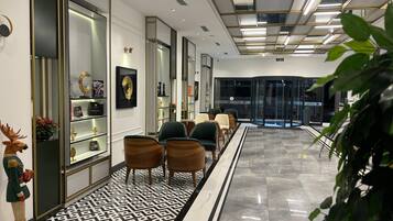A modern lobby with a patterned floor, seating area, and display cases with items.