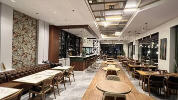 Ein modernes Restaurant mit einer langen Theke, Holztischen und einer Wand mit Muster.