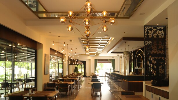 Un restaurante moderno con suelo de diseño geométrico, largas mesas de comedor y una zona de bar central.