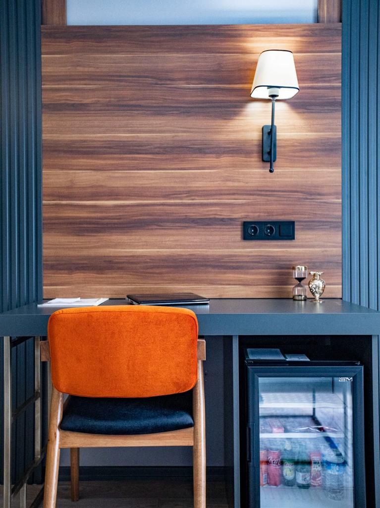 A modern desk with a lamp, a chair, and a mini-fridge.