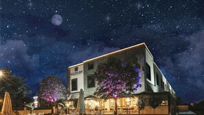 Un hotel con piscina, zona de estar exterior y cielo nocturno lleno de estrellas.
