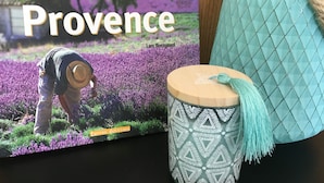 Un libro titulado 'Provence' de Lars Boesgaard, una taza con diseño y un bolso acolchado azul.