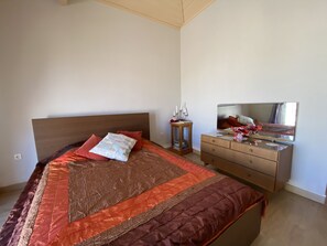 Un dormitorio con cama, cómoda, mesita de noche y espejo.