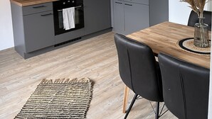 Een moderne keuken met grijze kastjes, een houten aanrechtblad en een hanglamp.
