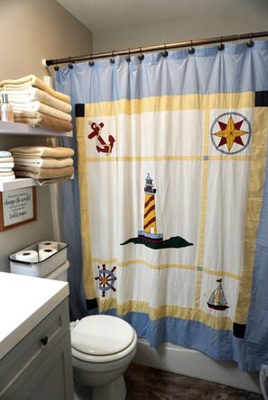 A bathroom with a toilet, a shelf with folded towels, and a wall-mounted toilet paper holder.