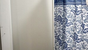 Een badkamer met een witte muur, een houten handdoekhouder en een douchegordijn met een blauw bloemenmotief.