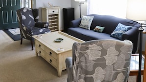 A living room with a dark blue sofa, a white coffee table, a patterned armchair, a wooden cabinet, and a lamp. - Vacation Home at Point Sebago Resort (Casco)