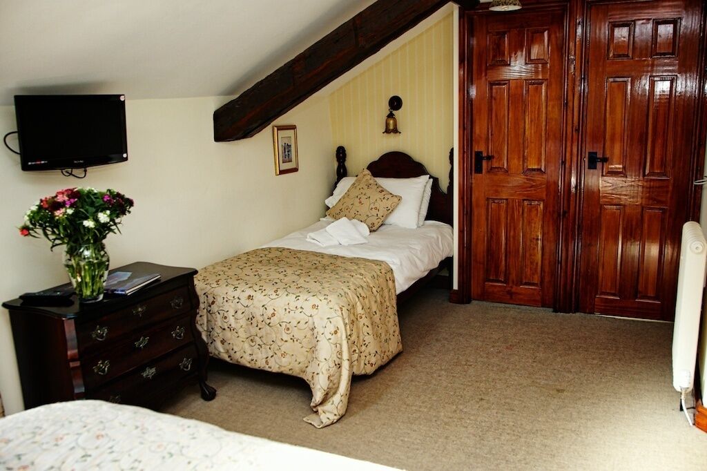 A bedroom with a bed, a dresser, a television, and a wooden wardrobe.
