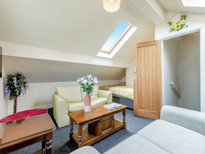 A loft-style room with a high ceiling, a skylight, a sofa, a coffee table, and a bed.