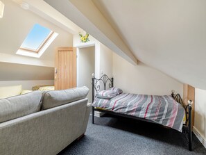Ein Schlafzimmer mit einem Bett, einer Schlafcouch, einem Oberlicht und einem Holzschrank.