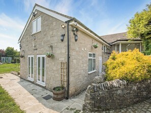 A stone house with a tiled roof, a small garden, and a stone wall.