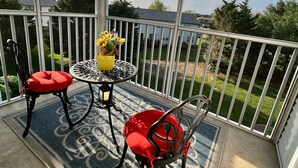 Ein Balkon mit Tisch, Stühlen und einem Teppich.
