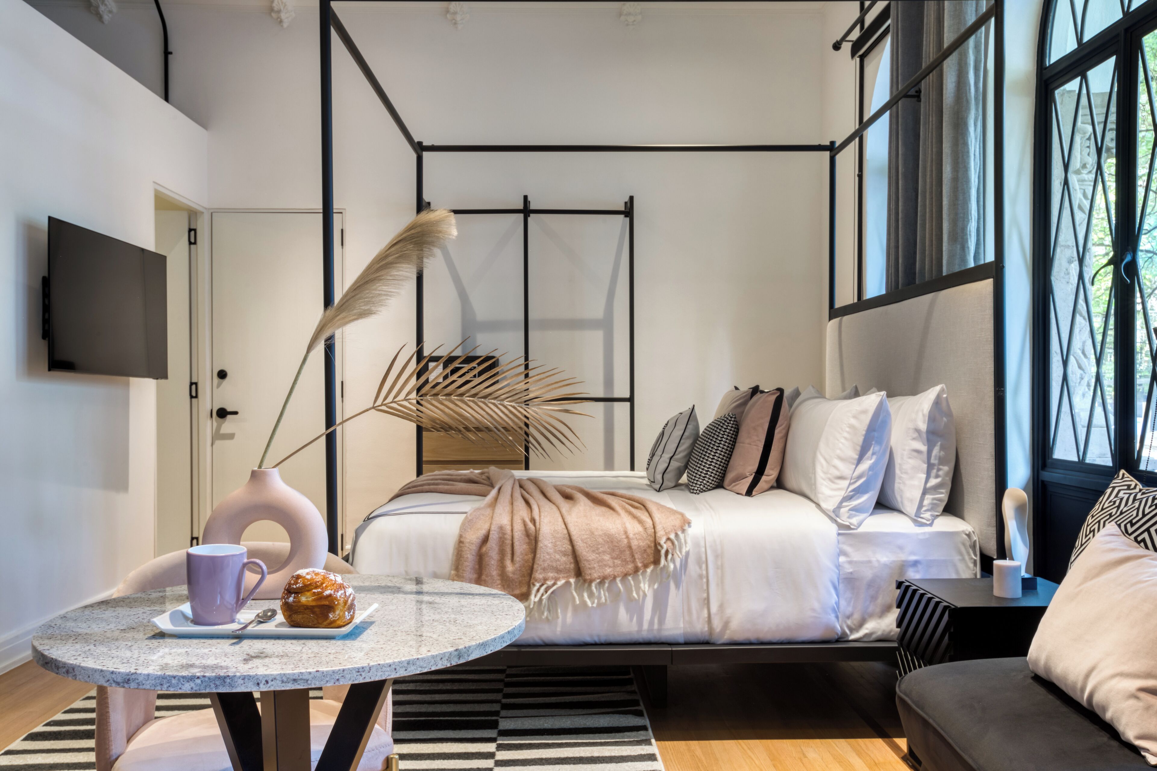 A modern bedroom with a bed, a sofa, a coffee table, and a TV.