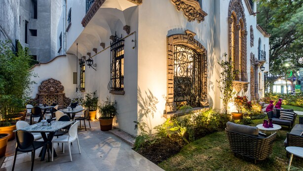 An outdoor patio with tables and chairs, surrounded by potted plants and a small garden. - UTOPIC Campos Elíseos by ULIV (Mexico City)
