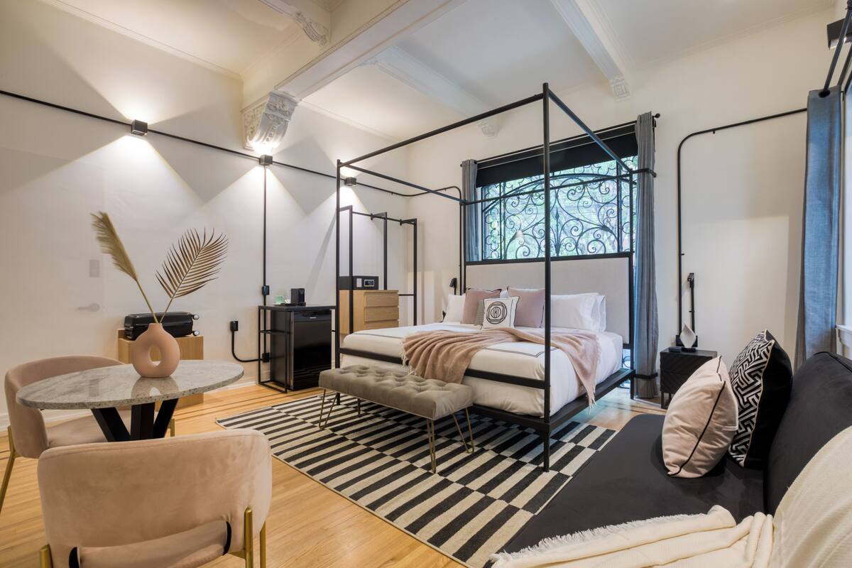 Una camera da letto moderna con un letto a baldacchino, un tavolo da pranzo rotondo e una piccola zona salotto.