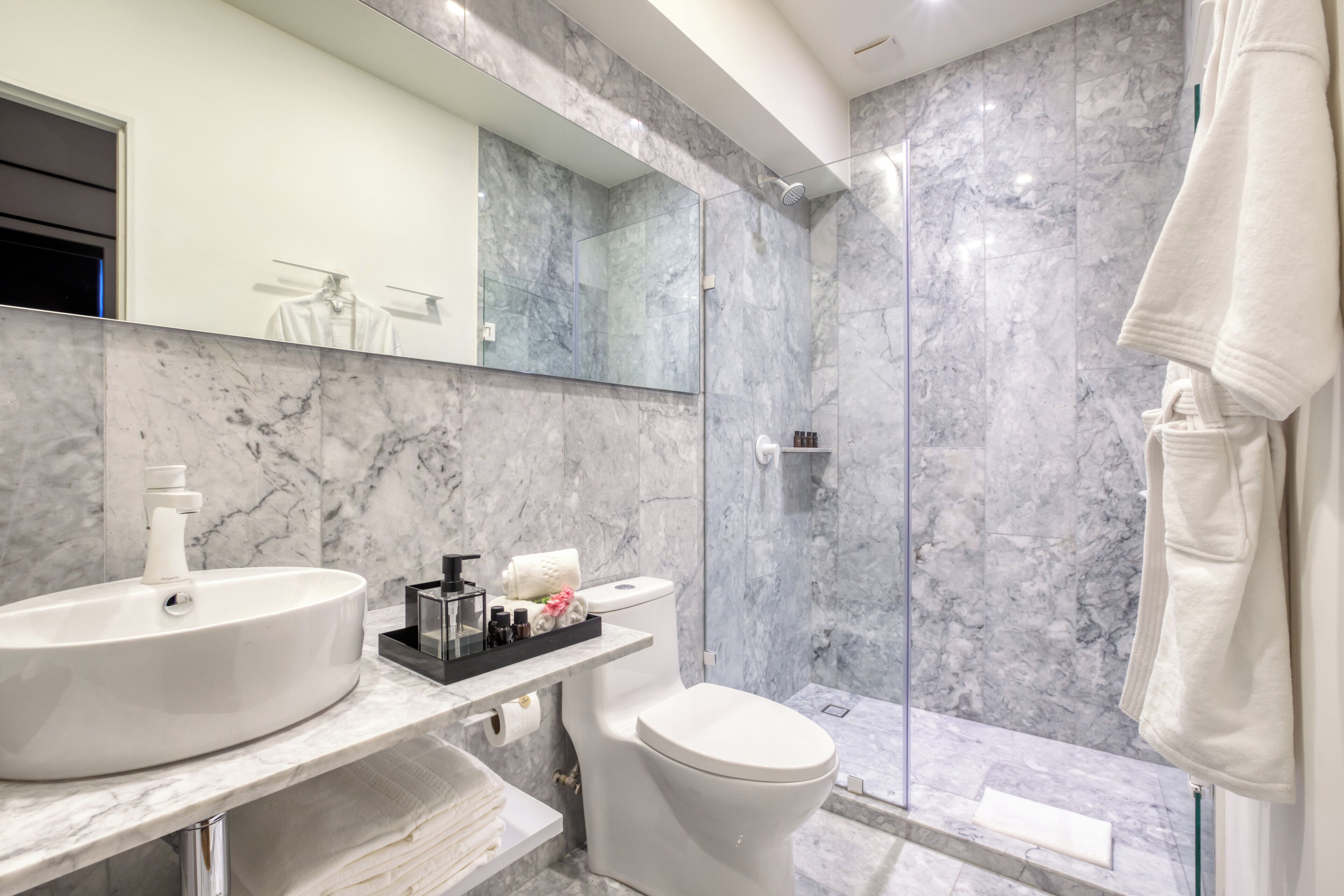 Un baño moderno con lavamanos blanco, inodoro y cabina de ducha de vidrio.
