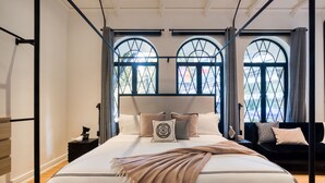 A modern bedroom with a large bed, two windows with curtains, and a view of the outside. - UTOPIC Campos Elíseos by ULIV (Mexico City)