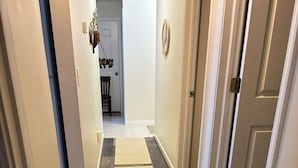 A hallway with two rugs, a door, and a wall-mounted light fixture. - Duplex in the country ten minutes from Frankenmuth-Betty’s Birch Run Road Place. (Millington)