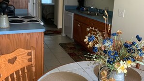 A kitchen with wooden cabinets, a stove, and a dining area with a table and chairs.