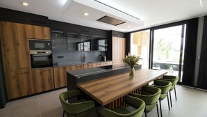 Una cocina moderna con una isla de madera, sillas verdes y un ventanal amplio.
