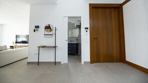 Una sala de estar moderna con un sofá, una mesita y una puerta de madera que da a un baño.