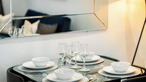 A dining table set with white bowls, wine glasses, and cutlery, reflecting a modern interior.