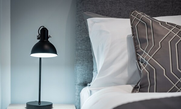 Ein Doppelzimmer mit einer modernen Lampe, einem gemusterten Kissen und Blick auf die Innenstadt.