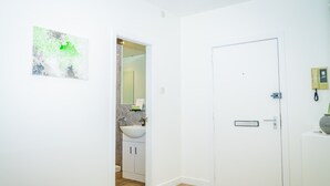 A clean, modern bathroom with a white sink, a mirror, and a door. - The Bond by Central Serviced Apartments - City Centre (Dundee)