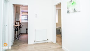 A modern apartment with a kitchen area, a radiator, and a painting on the wall. - The Bond by Central Serviced Apartments - City Centre (Dundee)