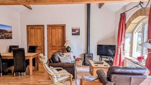 A cozy living room with a fireplace, wooden furniture, and a TV. - 2 bedroom accommodation in Wrelton, near Pickering (Wrelton, near Pickering)