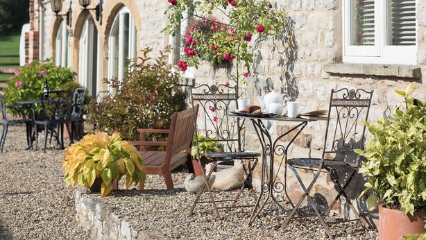 An outdoor seating area with tables and chairs, a bench, and potted plants. - 2 bedroom accommodation in Wrelton, near Pickering (Wrelton, near Pickering)