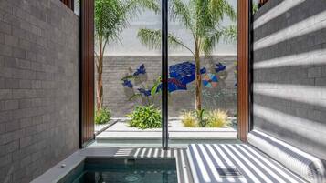 Zona de piscina interior moderna con pared de vidrio, una piscina pequeña y un banco.