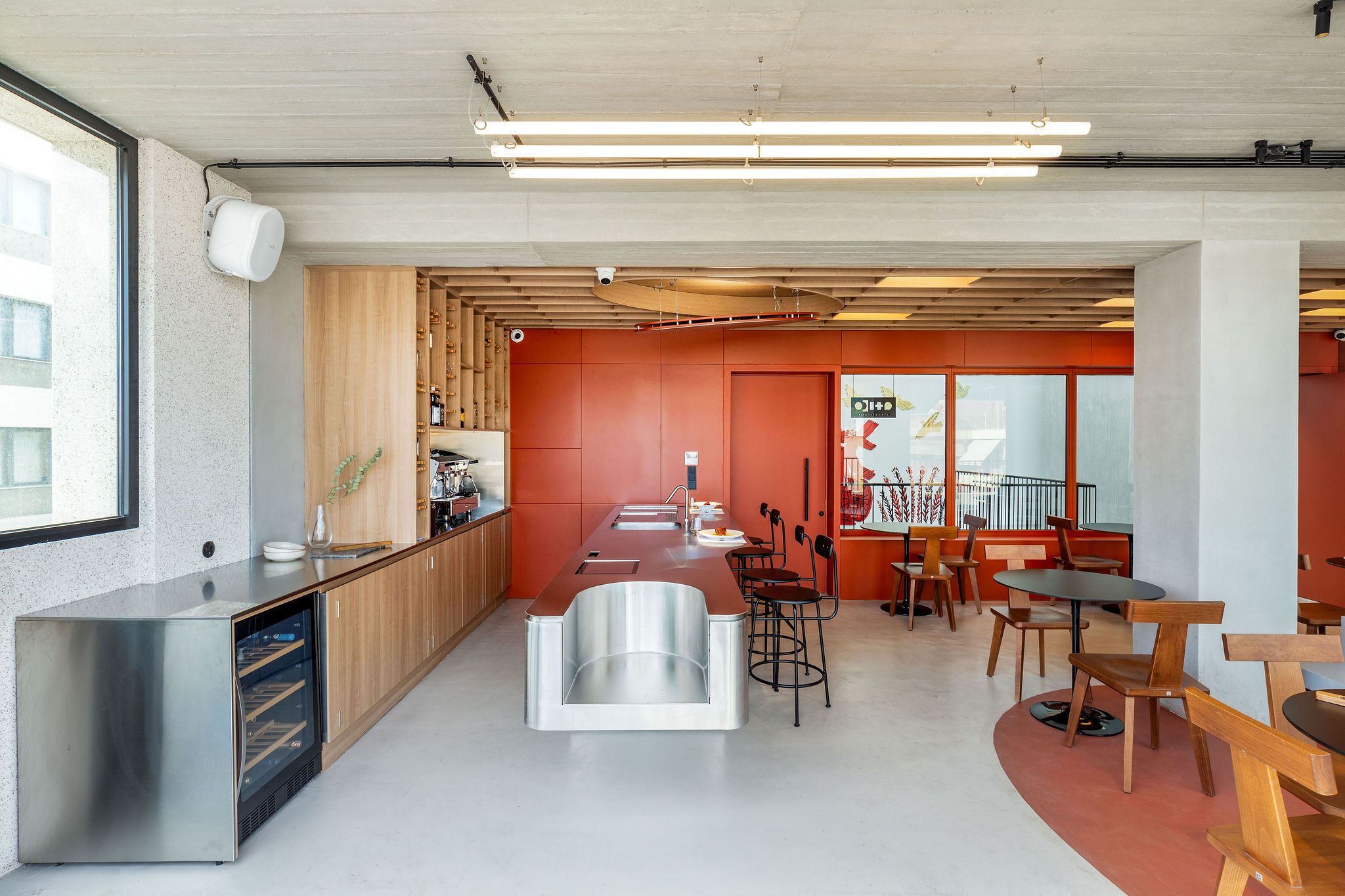 A modern kitchen with a stainless steel island, wooden cabinets, and a red accent wall.
