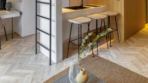A modern loft-style apartment with a mezzanine, a kitchen area with stools, and a herringbone-patterned floor. - The Newel Psychiko (Athens)