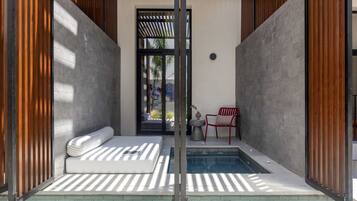 A modern spa area with a small pool, a massage table, and a red chair.